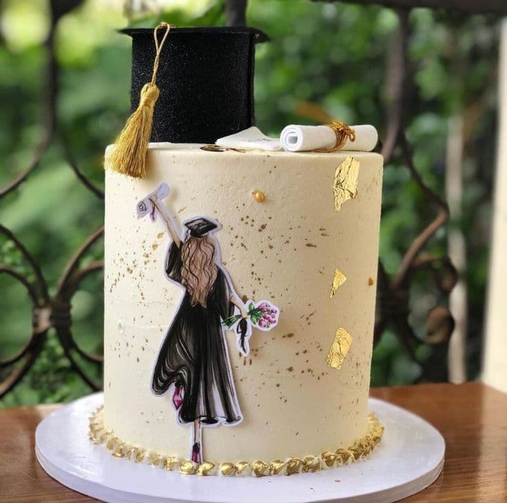 Pastel de graduación crema con birrete negro, detalles dorados e ilustración de una graduada.