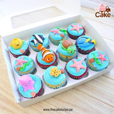 Doce cupcakes decorados con personajes de Buscando a Nemo y figuras marinas sobre glaseado azul.